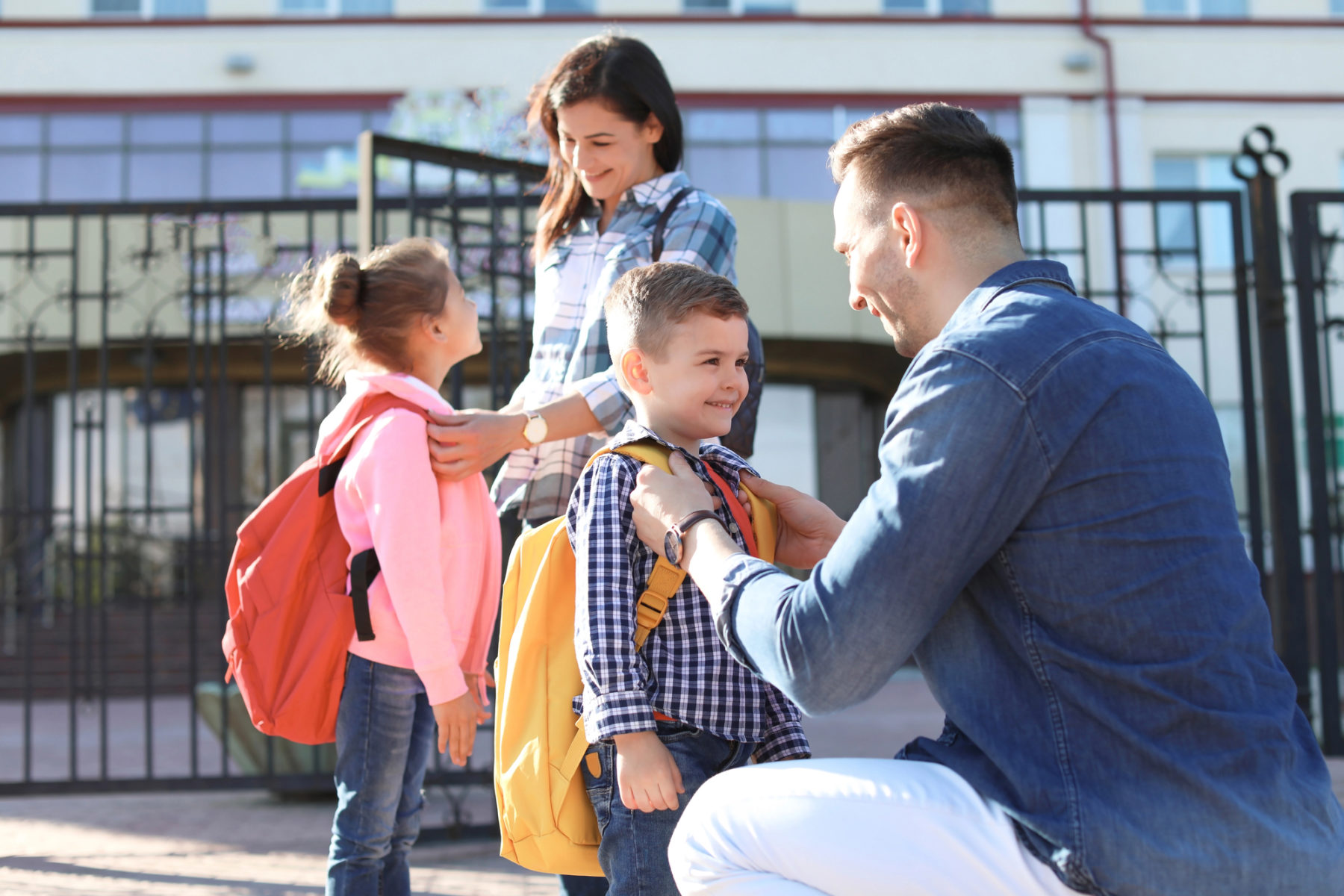 Des parents saluent leurs enfants alors qu'ils s'apprêtent à aller à l'école