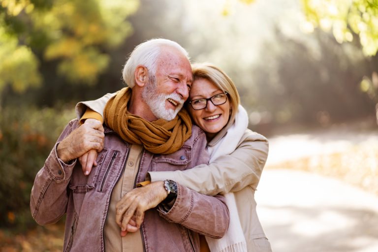 La complicité d'un couple senior heureux où la femme enlace son mari lors d'une balade dans la nature