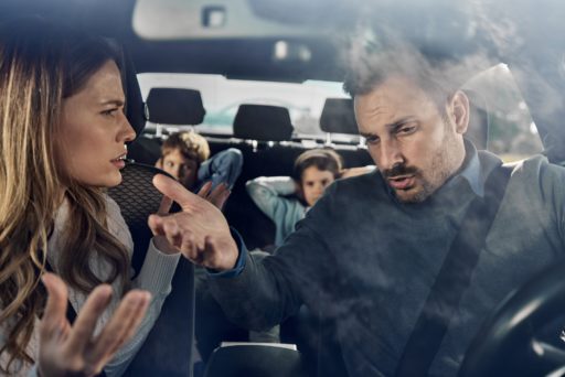 Une femme et un homme se dispute dans une voiture, les enfants derrière se bouchent les oreilles